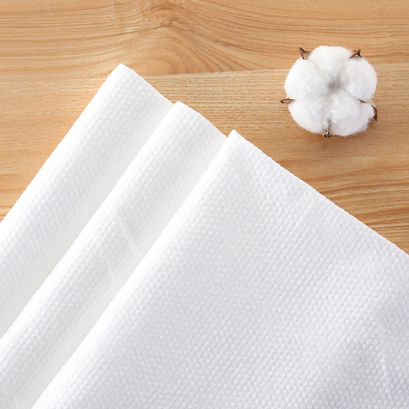 White textured travel towels arranged on a wooden surface