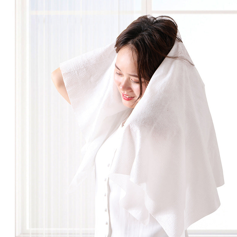 Expanded white travel towel being used to dry hair